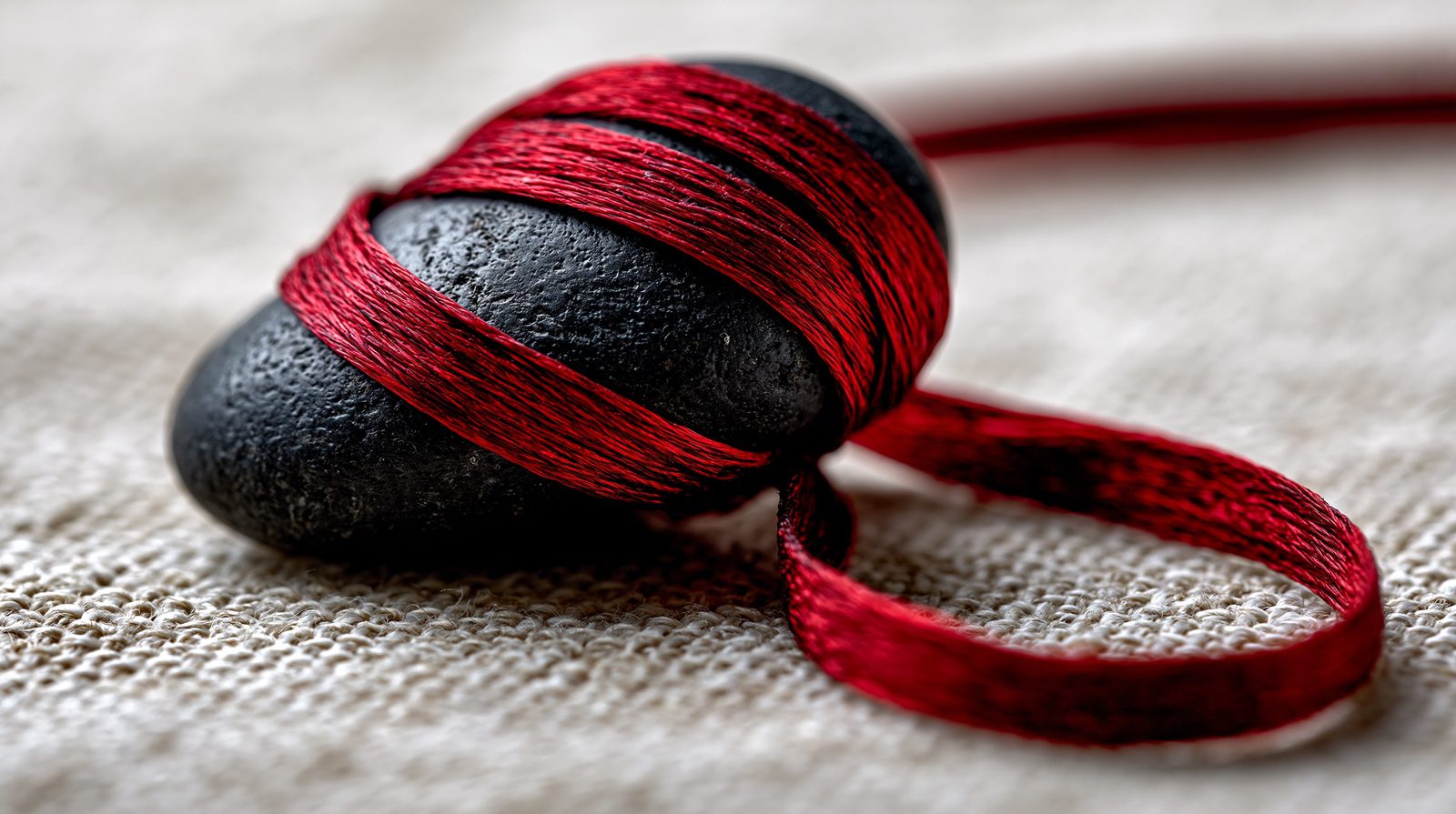 A red thread wound around smooth black stones